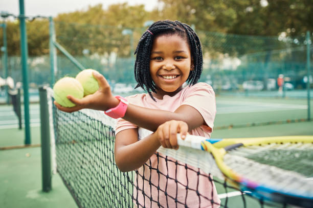 子供、テニス、ラケットとボールを持って外のスポーツコートで若い女の子とスポーツ。トレーニング、運動、トレーニング、トレーニングは、練習や幸せな笑顔でゲームのために外で女性� - tennis court sports training tennis net ストックフォトと画像