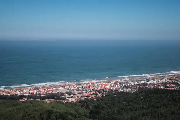 Praia de Quiaios landscape in Portugal. General view from viewpoint of beach and residential area showing tiny distant houses, the Atlantic Ocean, blue sky and trees