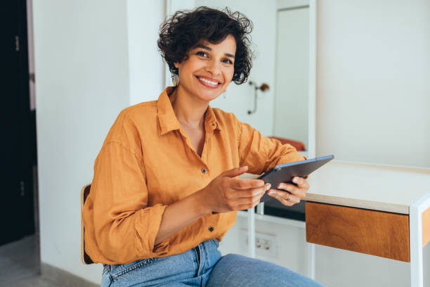 A Happy Beautiful Businesswoman Looking At Camera While Holding Her Tablet