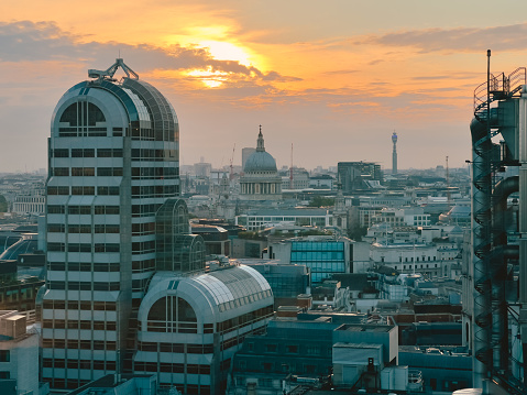 High angle view of the famous London skyline at golden hour. The view takes in the Lloyds building as well as the famous dome of St Paul's Cathedral in the distance.