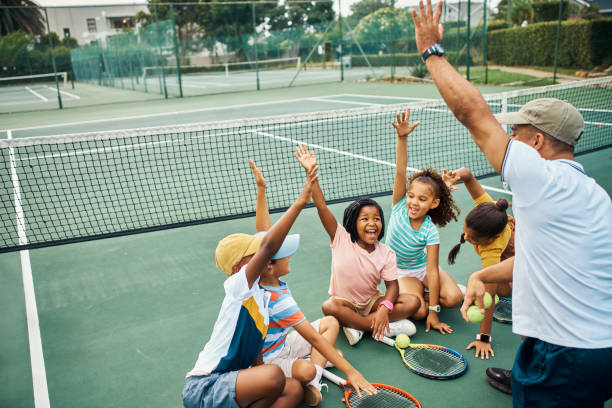 excited, hands up and tennis lesson for kids on court outside. coaching, training or learning enthusiastic children doing fitness workout or playing badminton sports with coach outdoors for exercise - racket tennis professional sport ball imagens e fotografias de stock