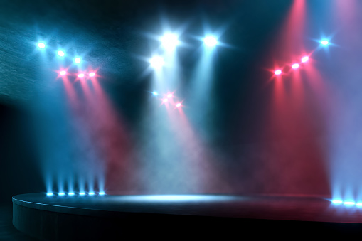 Empty performance stage illuminated by bright spotlights, with no people. Red and blue shining lights with dark surroundings and some smoke. Theatre or music venue scene with stage's edge visible and copy space. Digitally generated image.