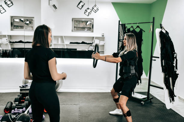 istock Female Working Out With Rubber Circle While Wearing EMS Bodysuit 1421338858