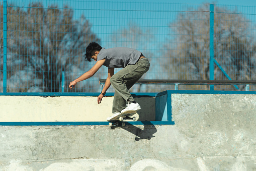 Latin skater boy doing trick in the concrete of skatepark. Copy Space