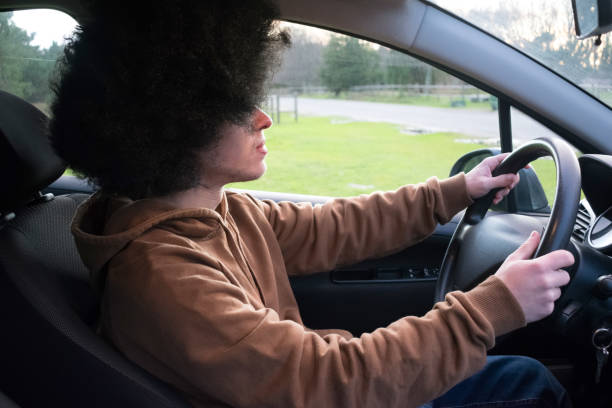 istock Young man with afro style hair driving a car 1421339882
