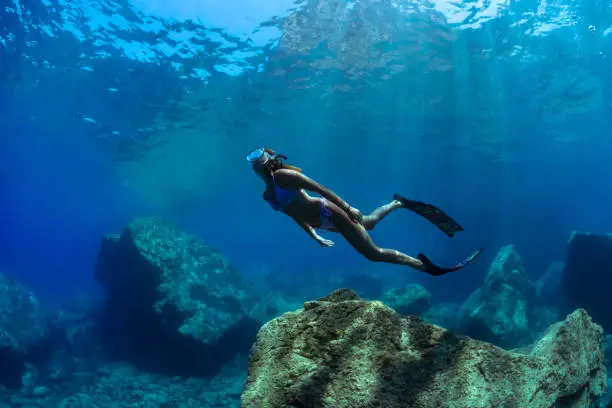 a girl dives in apnea in the crystal clear waters of the Mediterranean