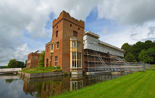 Oxborough, Norfolk, England - September 19, 2020: Oxburgh Hall under going roof repairs with scaffolding  and moat.