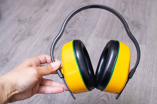 Yellow construction noise-cancelling headphones in hand close up