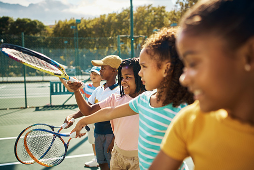 Tennis and sports training children, students or kids on a tennis court for sport education, fitness and exercise or workout. Young student class with racket learning how to swing and play the game