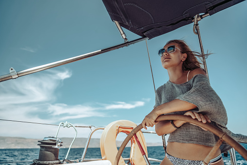 Beautiful Woman on a Helm of a Boat. Having Fun. Enjoying Amazing Sunny Summer Day. Water Sport. Peaceful Vacation.