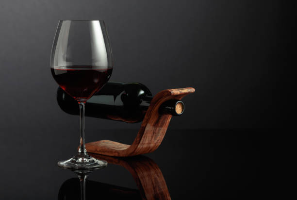 vino rosso su sfondo riflettente nero. - wine wine rack winery black foto e immagini stock