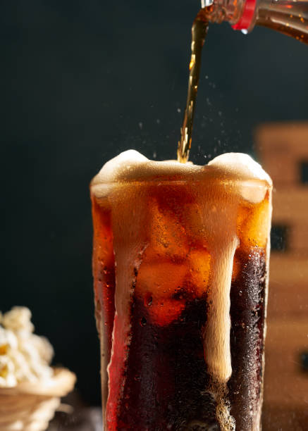 istock pouring cola soda into glass on wooden table with popcorn 1421358505