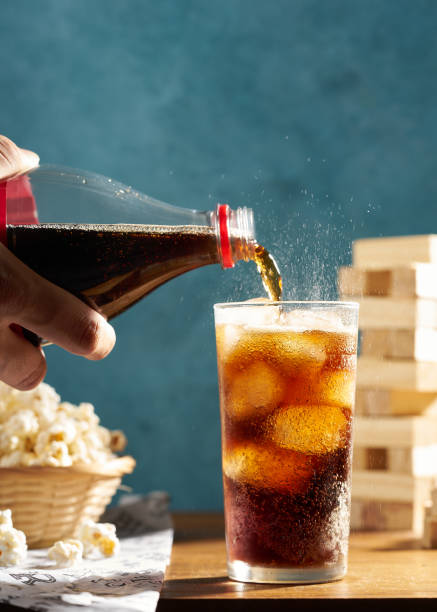 istock hand pouring cola into a glass on wooden table with popcorn 1421358513