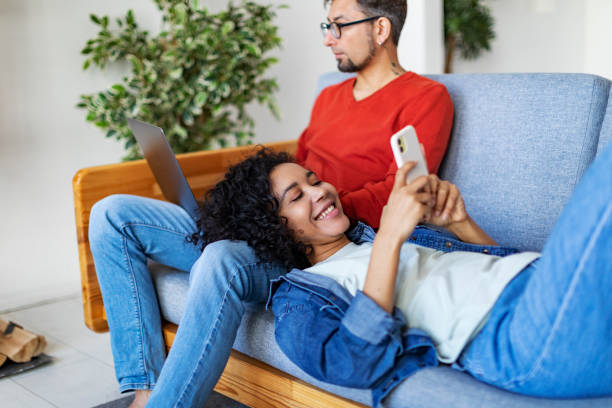 istock Multiracial couple using laptop and mobile at home for work and leisure 1421359263