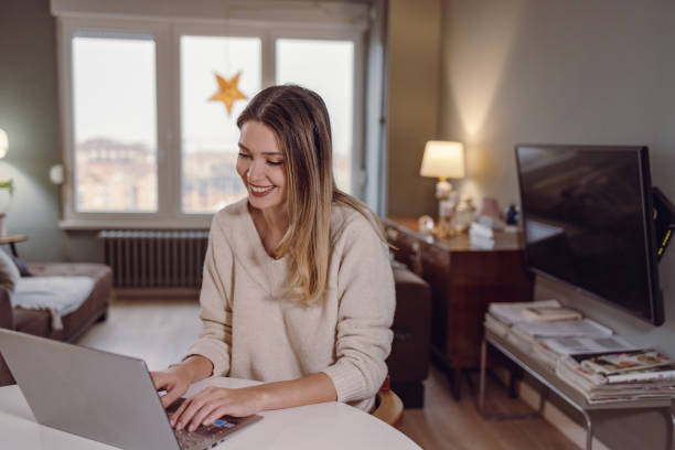 istock Young woman using laptop at home 1421361416