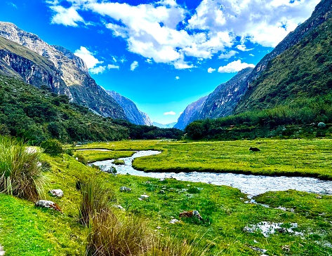River running through lush green valley surrounded by mountains.  Laguna 69 trek in Huaraz, Peru