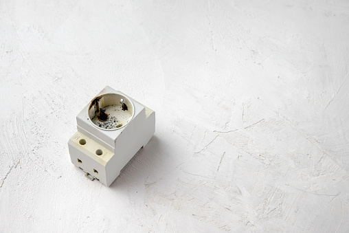 DIN rail socket after a short circuit in the power grid, gray concrete background, copy space