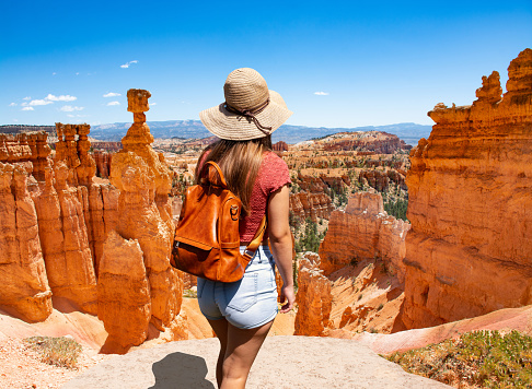 Woman standing next to Thor's Hammer hoodoo on top of  mountain looking at beautiful view. Bryce Canyon National Park, Utah, USA