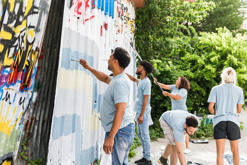The volunteers help paint a mural over the graffiti at the community center.