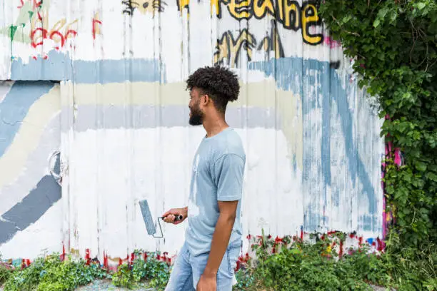 Photo of Young adult stands near the mural