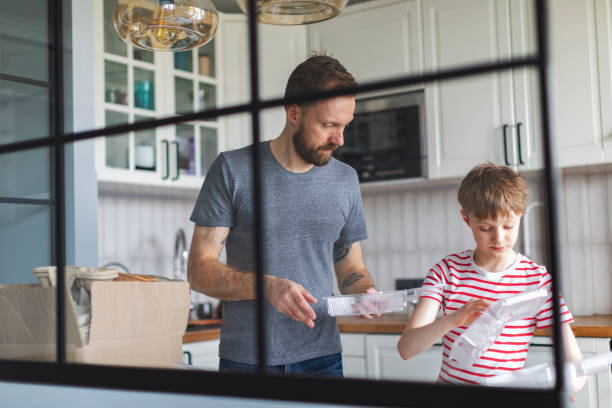 istock Father and son sorting waste at home for recycling 1421376135