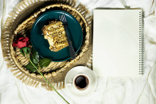 top view Morning breakfast in bed with coffee and cake, red rose flower and cup of coffee, agenda