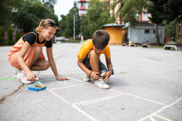 istock Cute tweenagers drawing a hopscotch diagram 1421378383