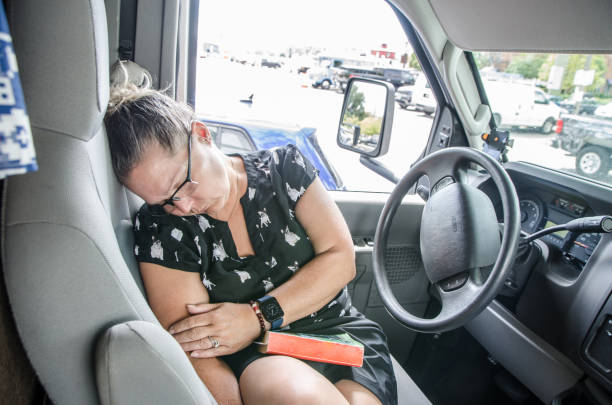 Mature woman sleeping in driver's seat of motorhome stock photo