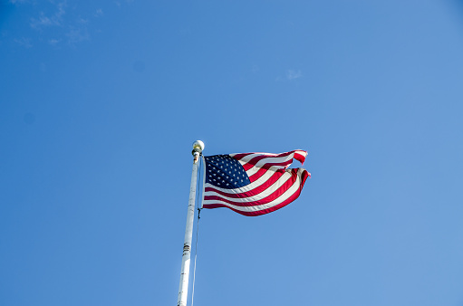 American flag on pole on clear sky background during summer day