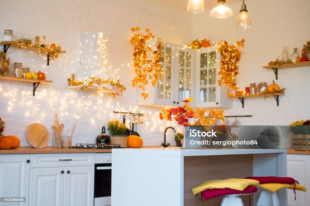 Autumn kitchen interior. Red and yellow leaves and flowers in the vase and pumpkin on light background Autumn kitchen interior. Red and yellow leaves and flowers in the vase and pumpkin on white background. Apple - Fruit Stock Photo
