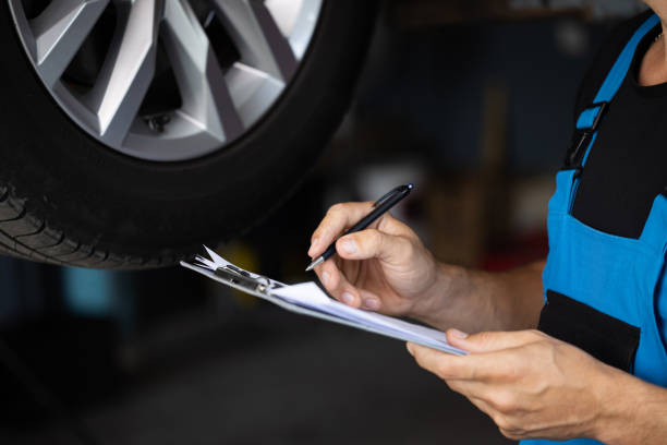 istock Mechanic inspects the car undercarriage way and makes a note on his inspection sheet. Automobile service, car mechanic. Car service employe inspect car. Modern workshop 1421387054