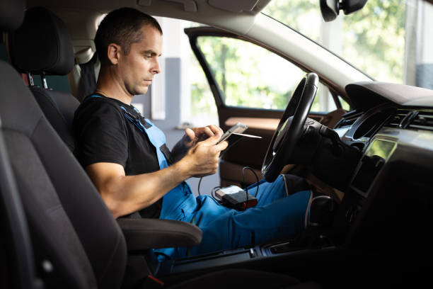 istock Mechanic sitting in car and working on laptop while doing vehicle diagnostic test in auto service garage. Automotive mechanic running diagnostics software on tablet computer. 1421387422