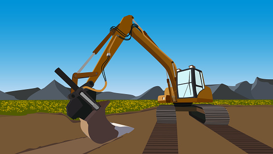 Color excavator on field with flowers and mountains behind with blue sky. Excavator bucket on ground and caterpillar tracks.