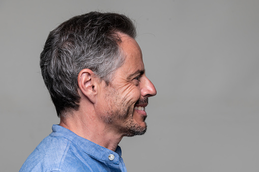 Smiling man profile mugshot on gray background