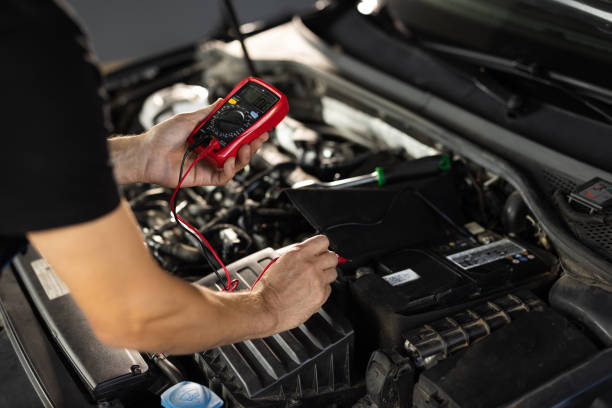 istock Automobile diagnosis. Car mechanic repairer looks for engine failure on diagnostics equipment in vehicle service workshop. Professional car mechanic check battery voltage with electric multimeter 1421389267