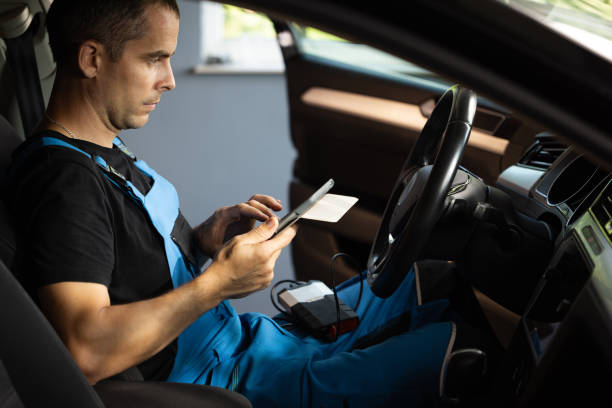 istock Automotive mechanic running diagnostics software on tablet computer. Mechanic sitting in car and working on laptop while doing vehicle diagnostic test in auto service garage 1421389416
