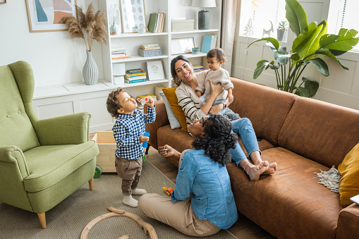 Young mothers playing with kids in living room.