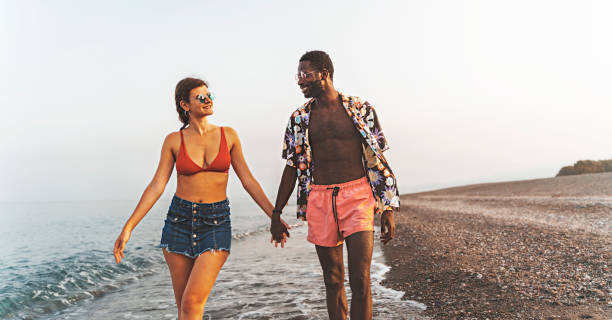 istock Multiethnic couple walking in the beach 1421394512