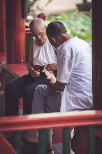 Chongqing, China - August 2019 : Two senior chinese men playing cards in public park
