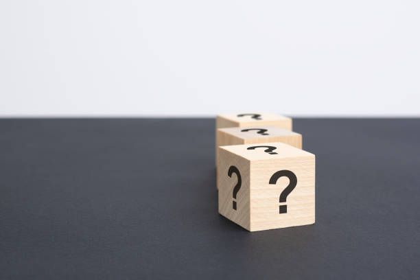 istock staggered row of three wooden blocks with question marks black on black table, copy space 1421395523