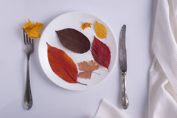 istock creative autumn concept canteen table setting autumn leaves on a plate on a white background 1421396435