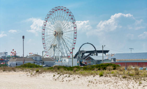 A large ferris wheel pauses to reload in sunset light at a small midway.  Tilt shift lens effect.