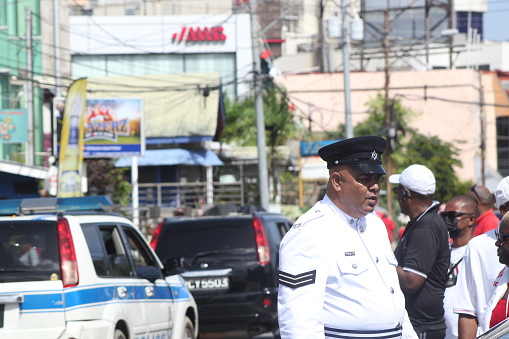 Port of Spain, Trinidad - August 31, 2022: \nCandid shot of a senior police officer on duty interacting with the crowd on the street for the Independence Day parade