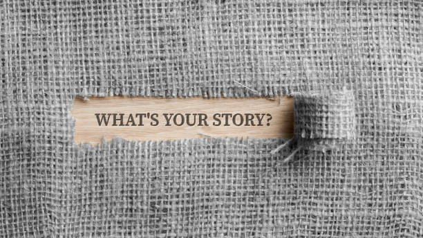 Monochrome image of a rough linen fabric with a torn window in the middle with a Whats your story? sign in it stock photo