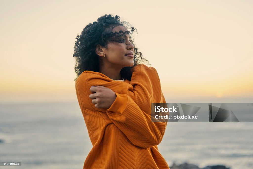 Relax, freedom and self love with a woman at the beach with the sea or ocean and horizon in the background. Water, nature and view with a young female outside and the wind blowing in her hair One Woman Only Stock Photo