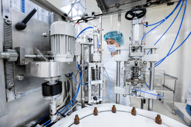 impiegata in un laboratorio farmaceutico visto mentre controllava il processo di produzione di farmaci - macchina per la produzione farmaceutica foto e immagini stock