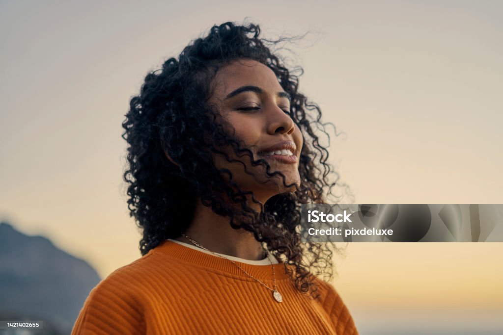 Happy woman in nature, sunset sky peace and smile breathing co2. Wellness beauty, clear outdoor sky and
fresh wave of calm. Eyes closed, asthma treatment air and girl with curly hair relaxed face. Tranquility Stock Photo