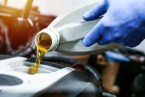 istock Car oil is pouring into the engine close up. 1421405034