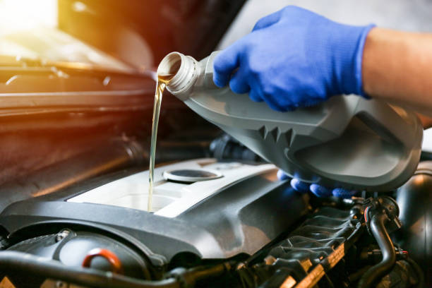 el aceite del coche se está vertiendo en el motor de cerca. - motor oil bottle fotografías e imágenes de stock