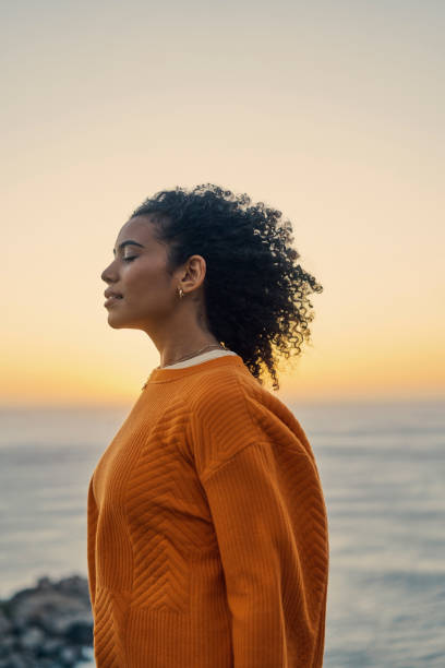 mentalidad relajada, zen y libertad de una mujer en el agua del océano, la playa y el mar en la naturaleza al atardecer. calma y energía positiva de una joven marroquí disfrutando del sonido de las olas de contenido por la noche - beach sea zen like nature fotografías e imágenes de stock